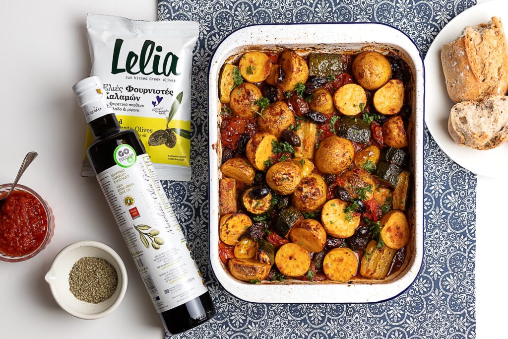 Ahjuvormis röstitud kartulid, suvikõrvits ja Kalamata oliivid tomatikastmes, kõrval Kreeka oliiviõli ja Lelia küpsetatud oliivid.